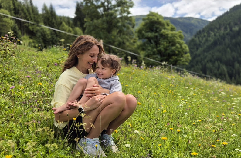 Alex mit Kind auf einer Blumenwiese